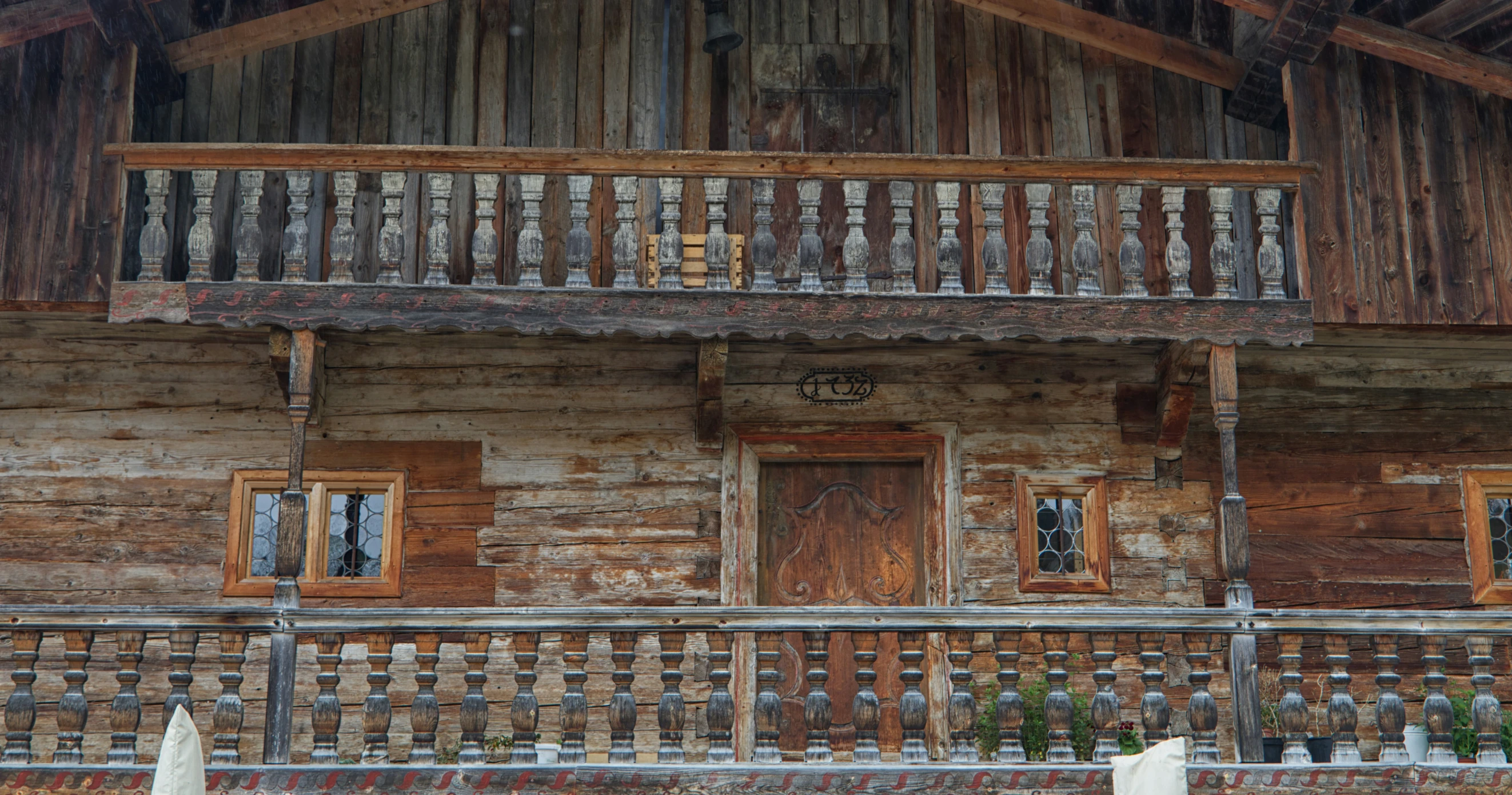 an old fashioned log house with brown doors and wood railing