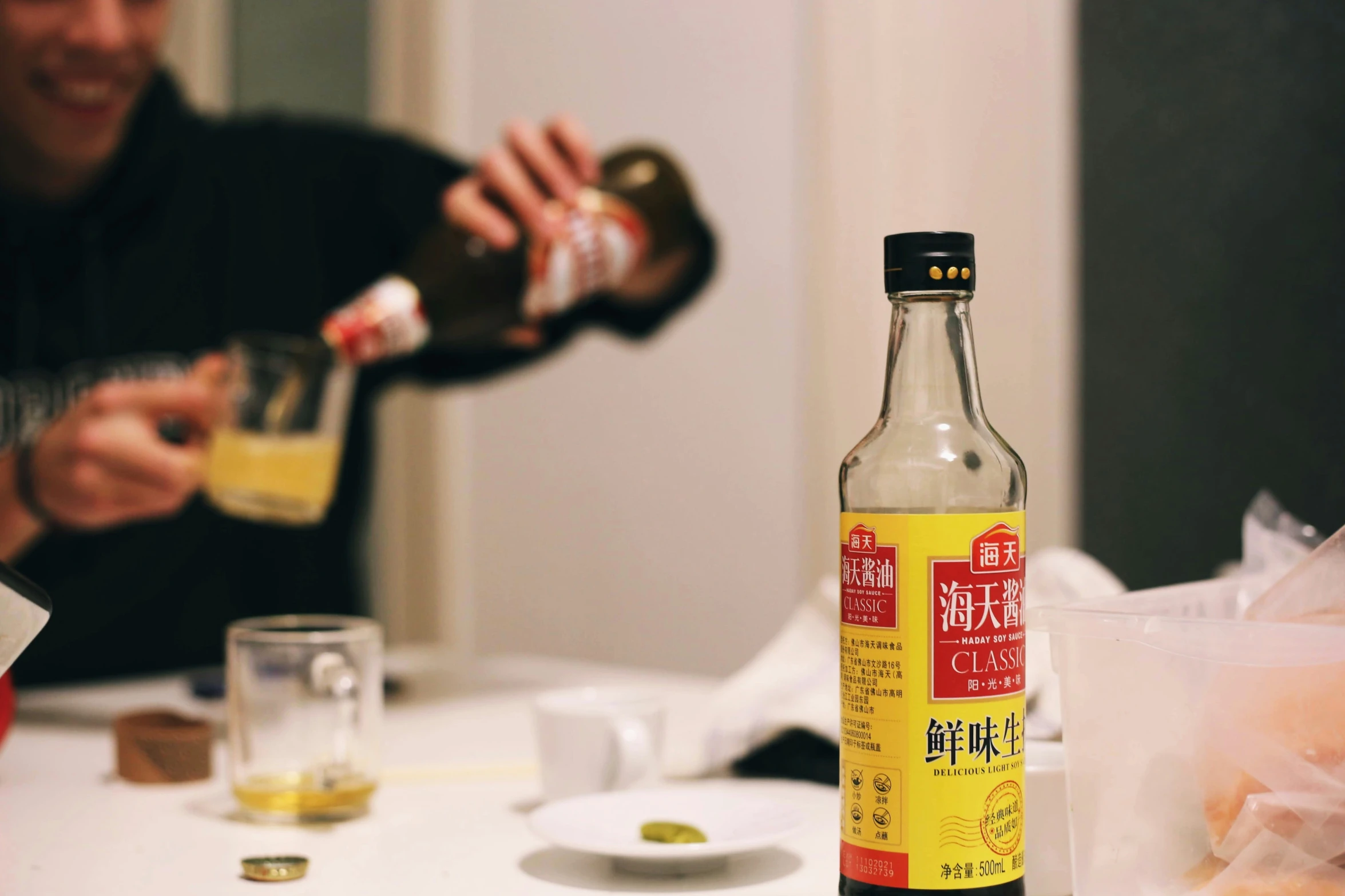 a man pours a bottle of sake with a glass of beverage