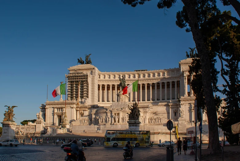 a large white building with three columns and some flags flying