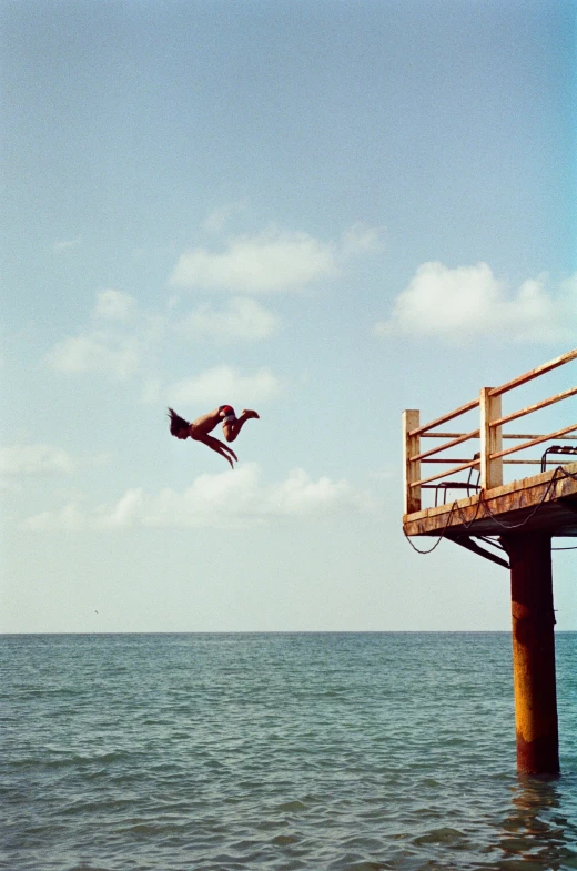 the seagull flies next to the fishing pier in the blue sky