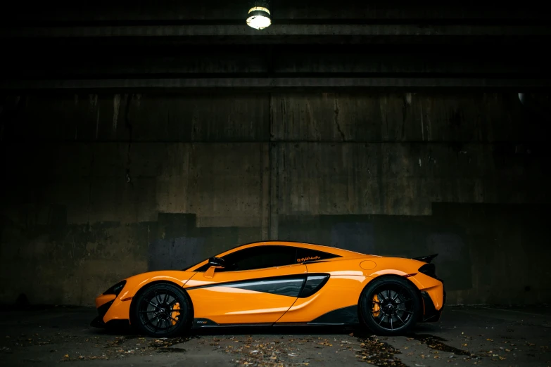 a very orange sports car parked in an underground spot