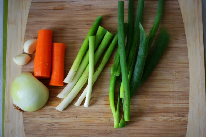 onions, carrots, green onions and celery on a  board