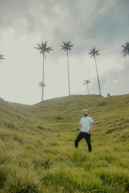 a man in a hat walking up a hill with palm trees in the background