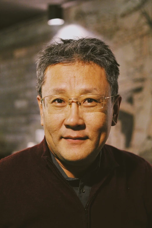 an older asian man wearing glasses in a dark room