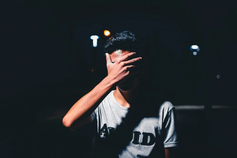 young man covering his eyes at the end of his night