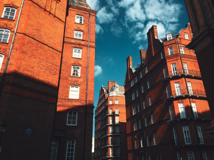 brick buildings and cars in front of clouds and blue sky