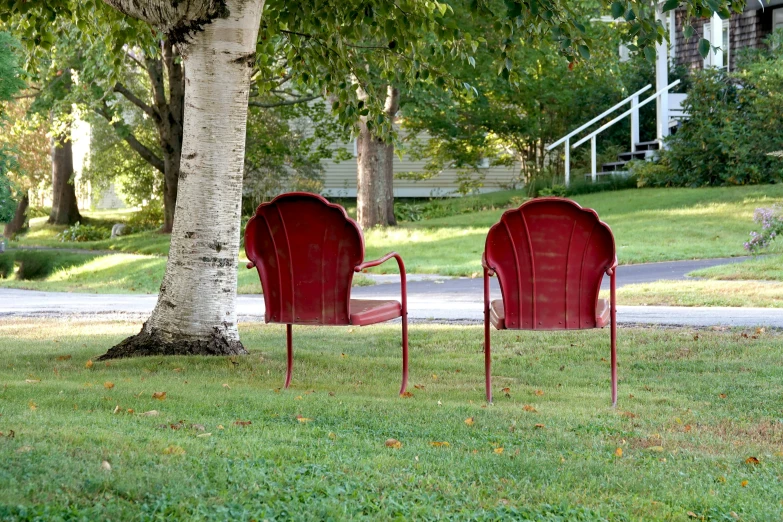 two red chairs sitting on top of a lush green park