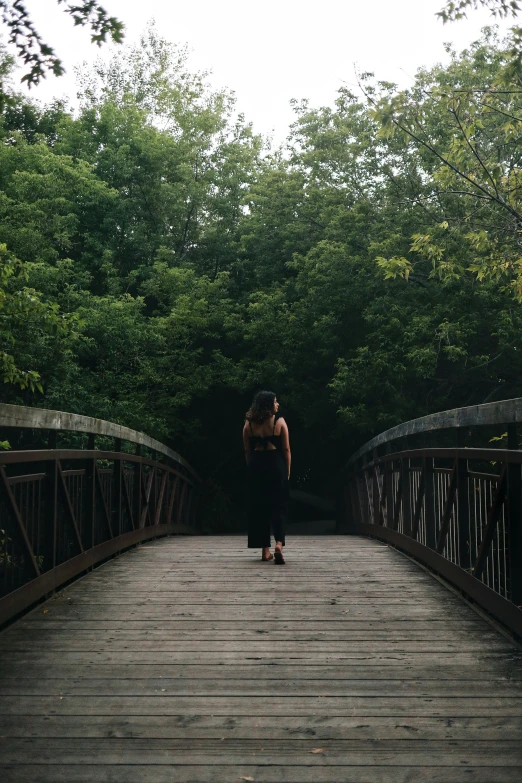 there is a woman holding onto her arms while standing on the bridge