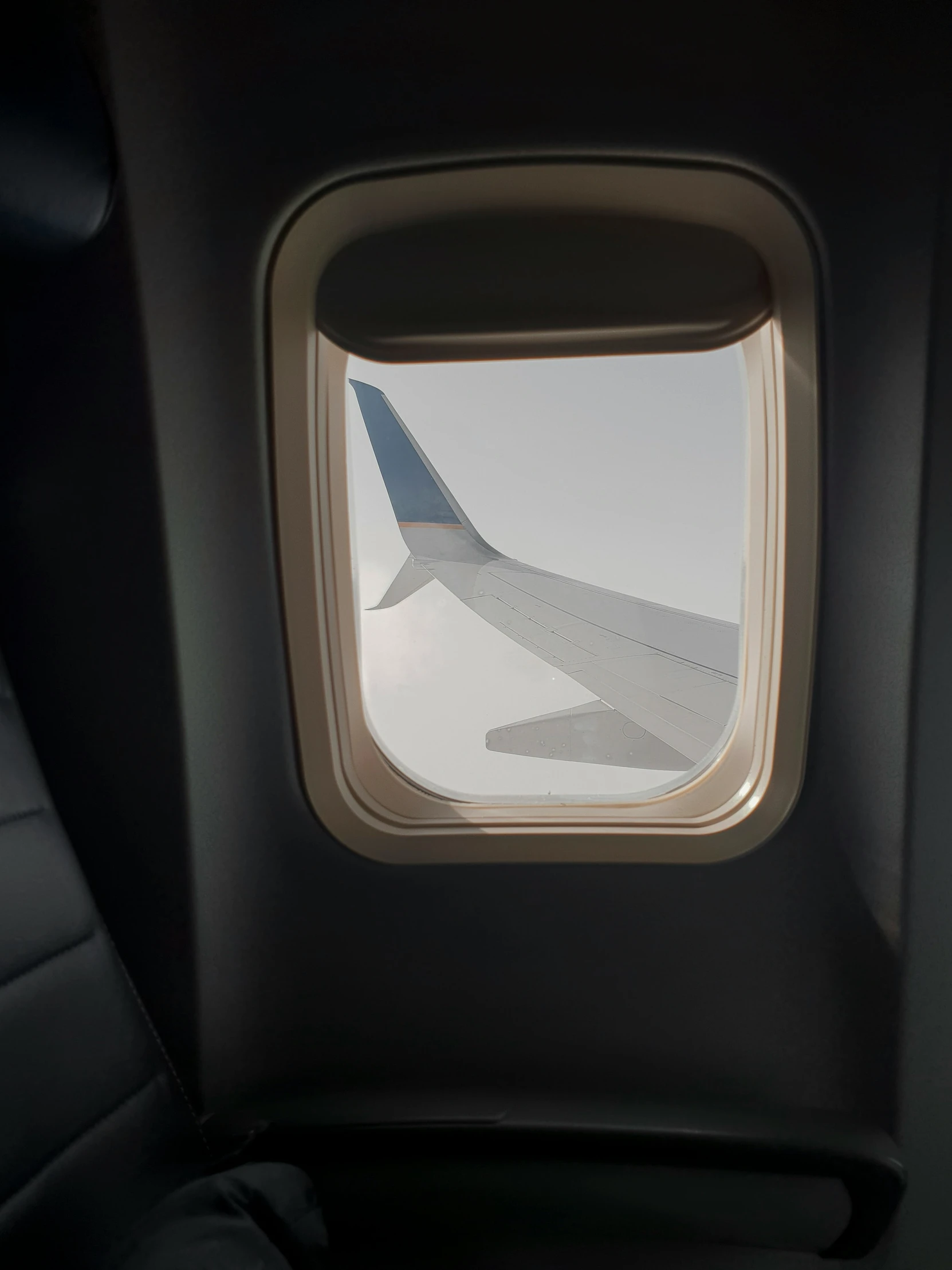 an airplane window, showing a view of the wing and the sky