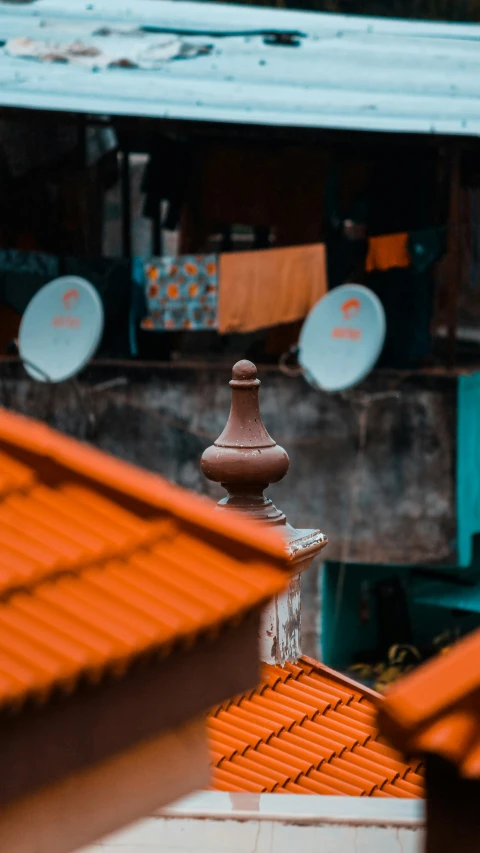 the roof tops of a building with orange tiles and an old looking birdcage