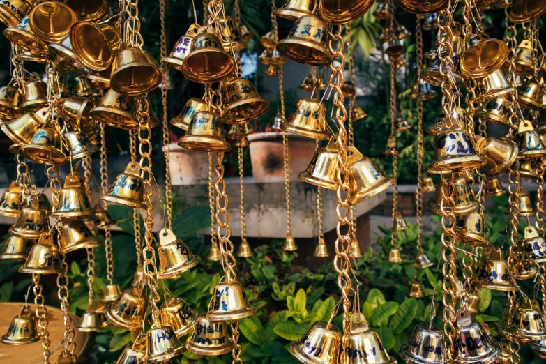 many gold bells are hanging from chains on the ground