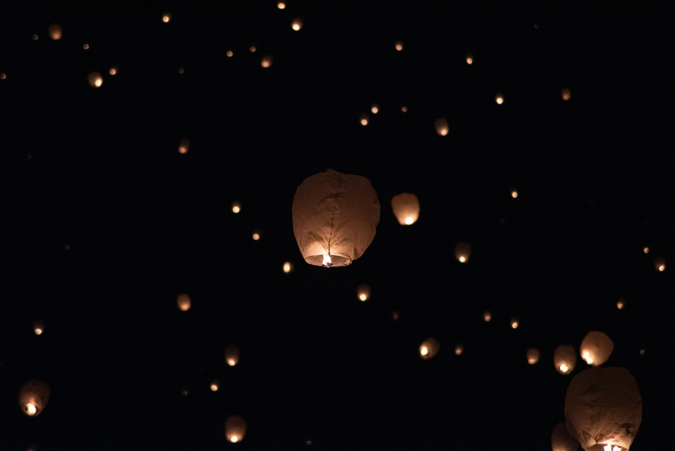 the sky is filled with flying lanterns at night