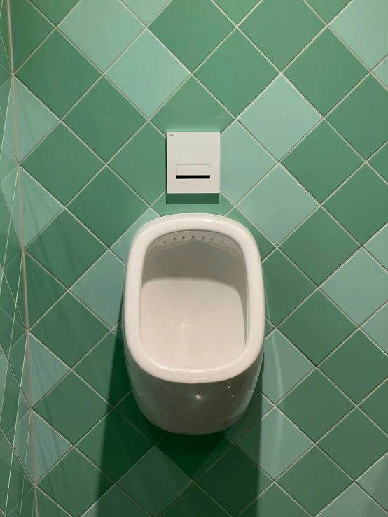 an aerial view of a white urinal and green tiled wall