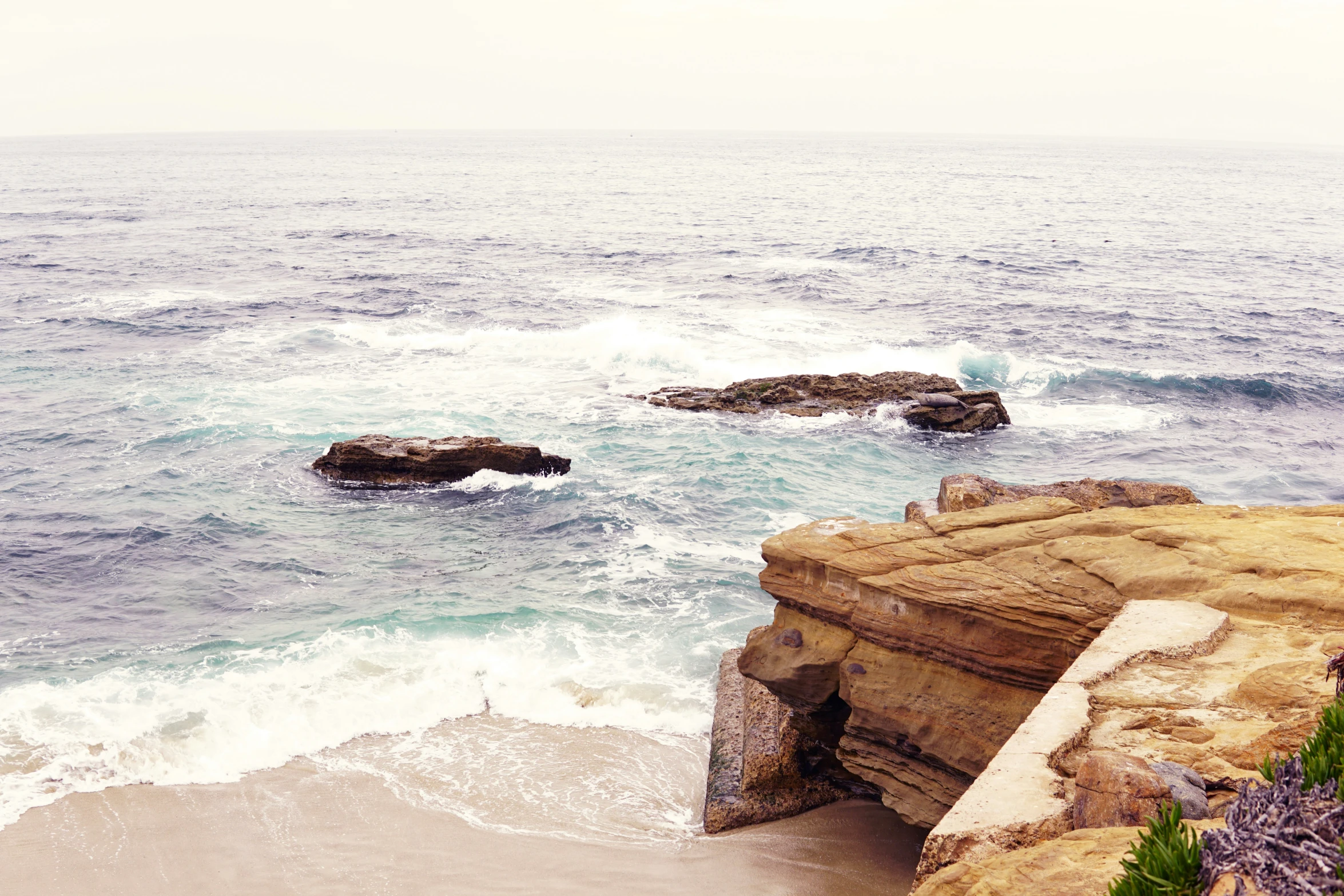 a rocky cliff face with water and rocks near by