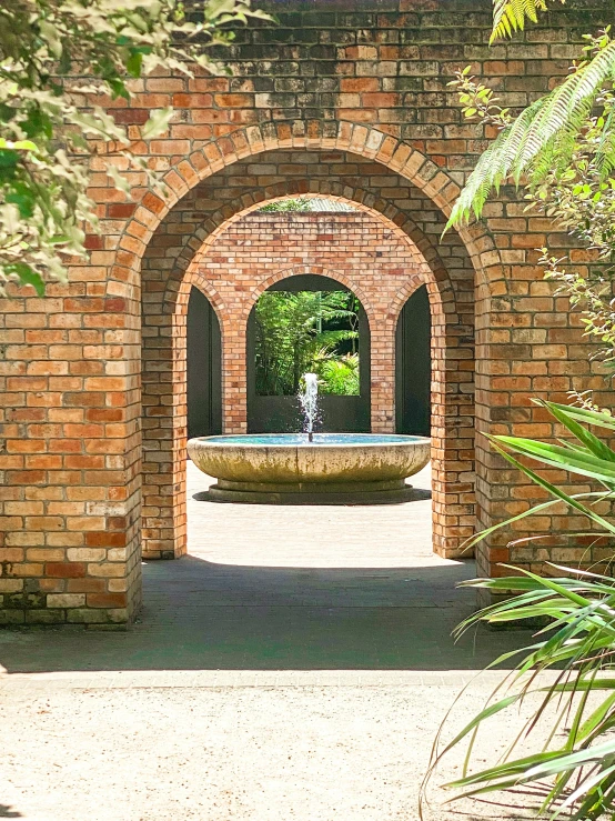 a brick archway has an elegant fountain in between two arches