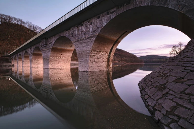 a bridge spanning a lake with a reflection in the water