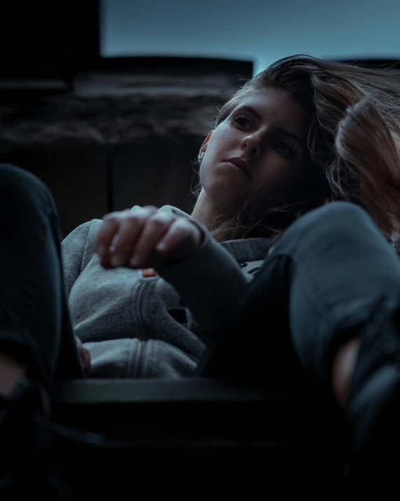 a woman is sitting in the dark and touching her finger