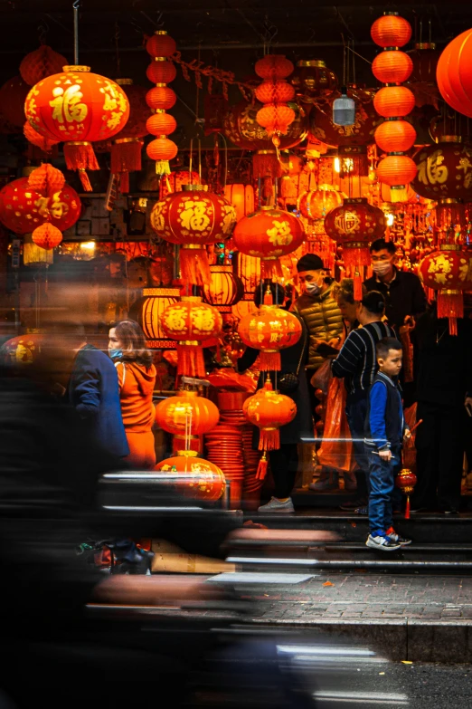 people stand outside in front of orange lanterns