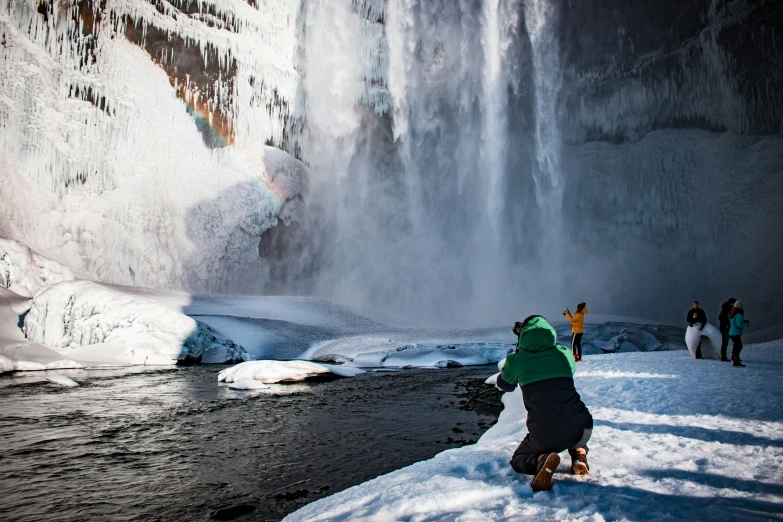 people standing around a waterfall and snowshoes