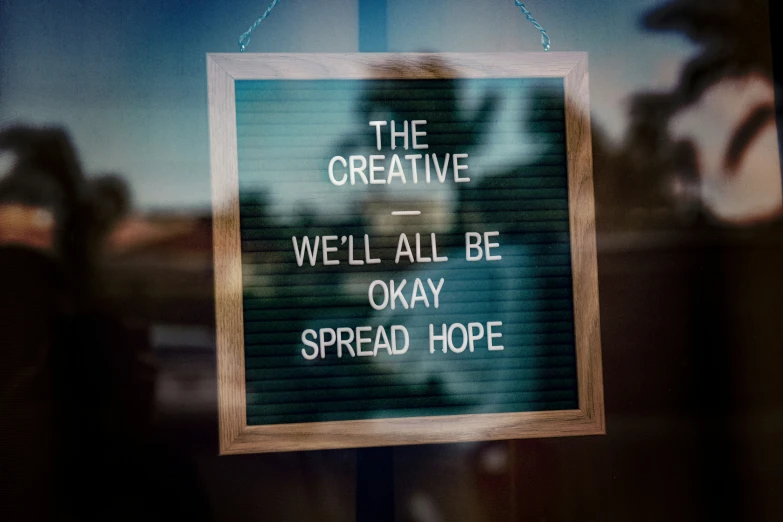 a po of a sign in a window saying the creative we'll all be okay spread hope