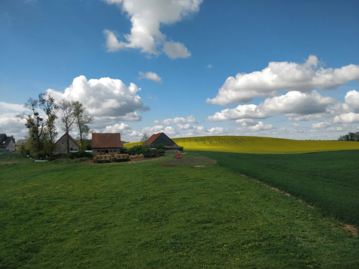 an open field with houses and clouds overhead