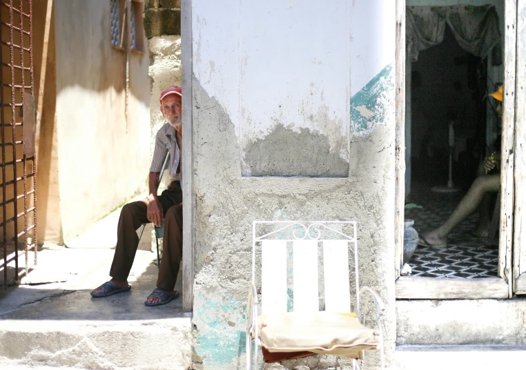 a man sitting on the side of a building next to a chair