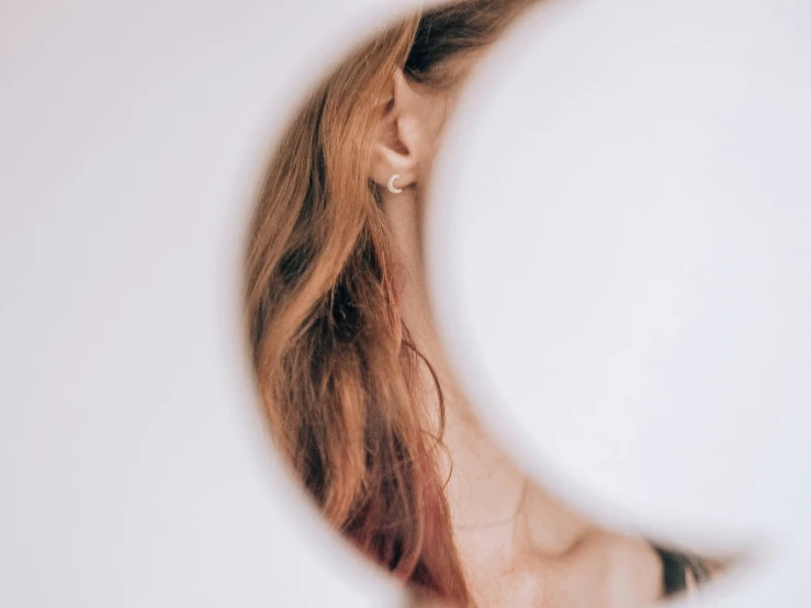 a closeup of a woman's head with the crescent of a half - moon in the background