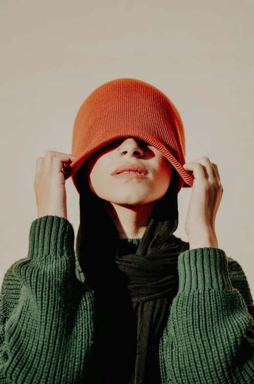 a woman in a green sweater wearing a red beanie