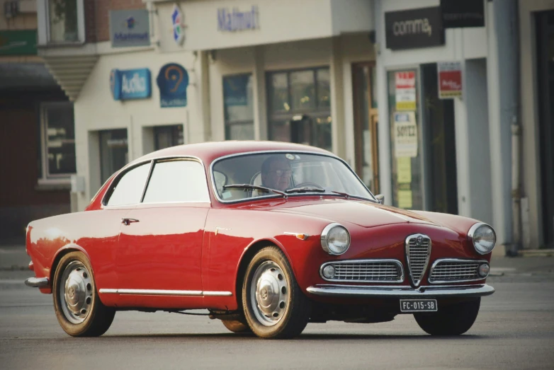 a red classic car parked in front of a store