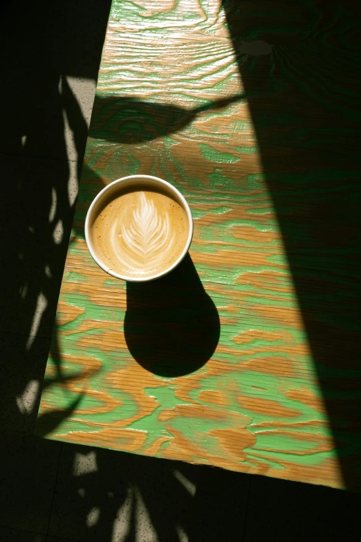 a shadow of a mug on top of a green table