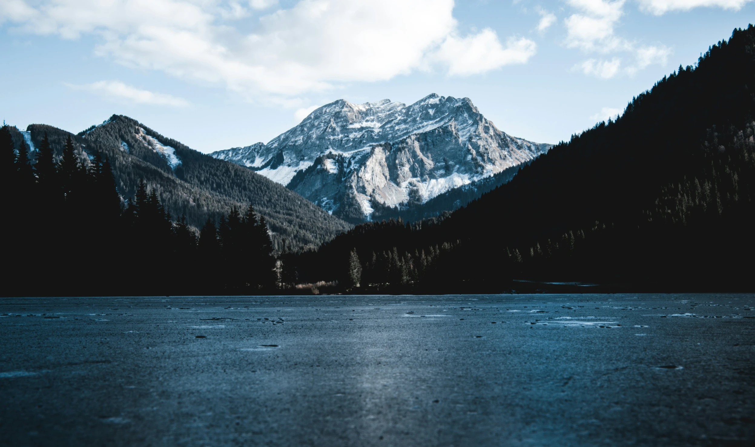 a lake with a mountain and blue sky in the background