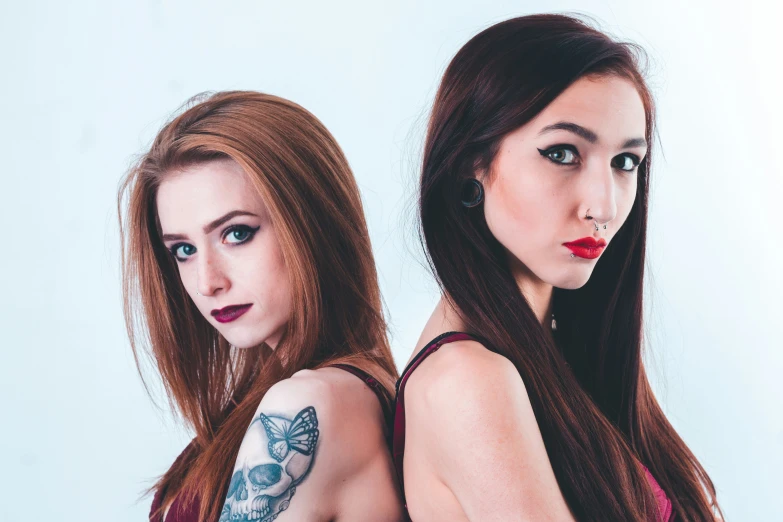 two women in red are side by side with a big tattoo