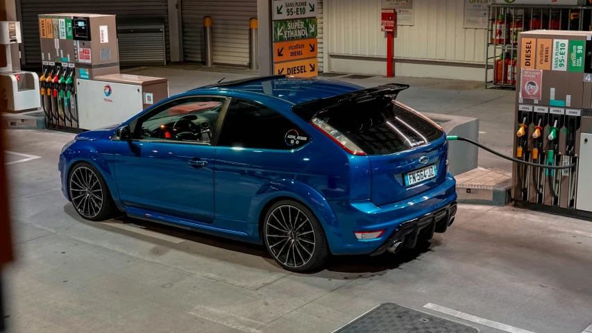 a blue car with its hood up parked in a parking garage