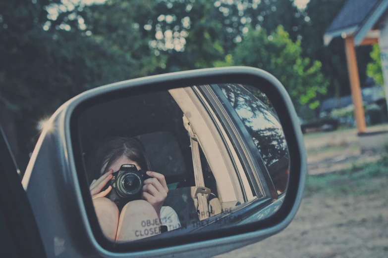 a person in a car takes a picture in a rear view mirror