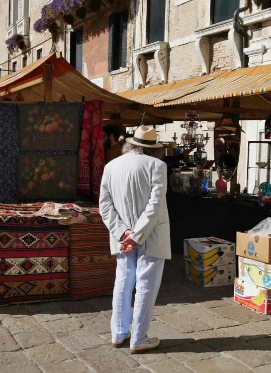 a man walking on the sidewalk near a pile of cloth