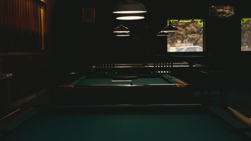 a room with pool tables and two lamps