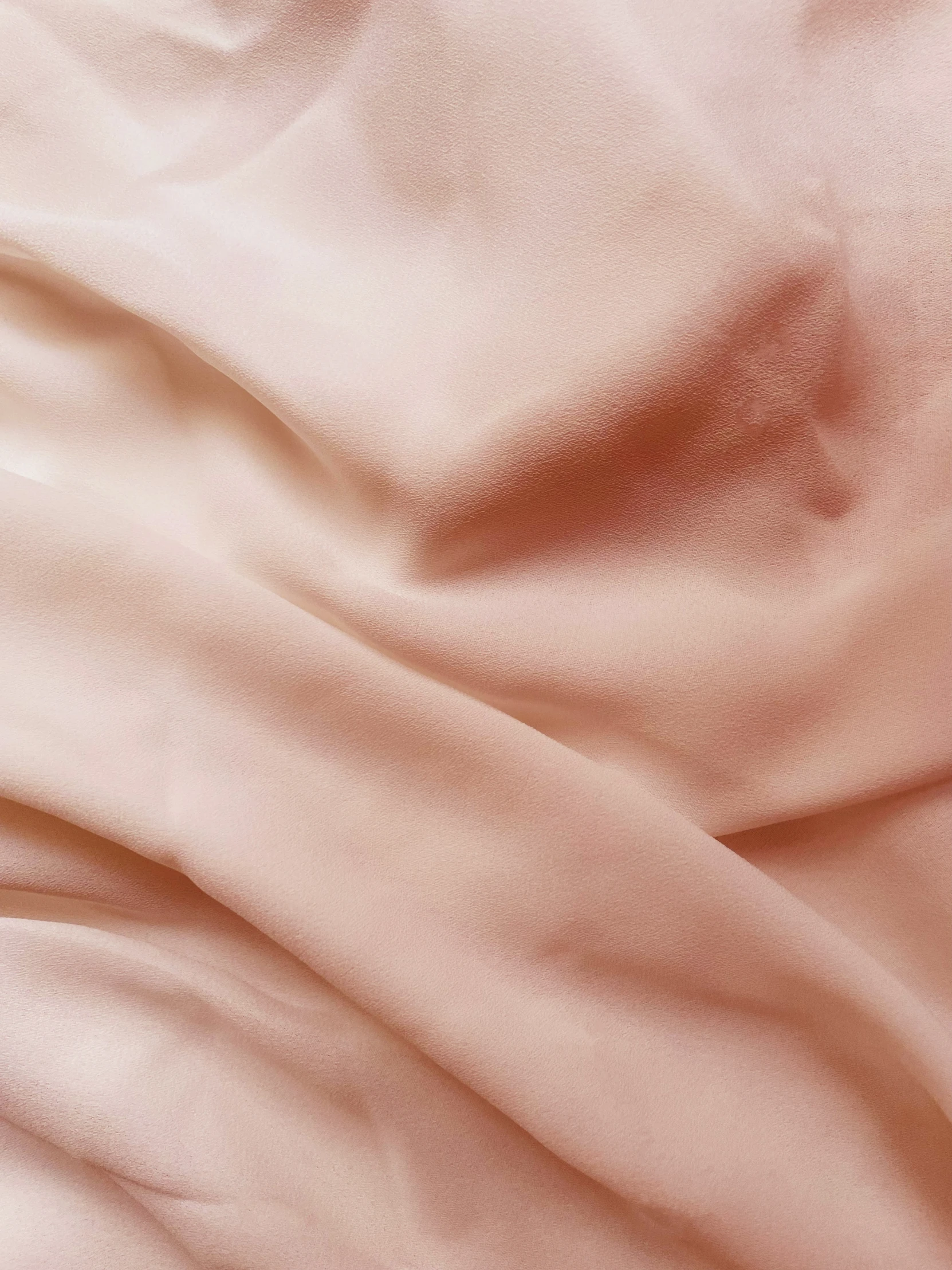 the bed has a pink sheet that is not made up