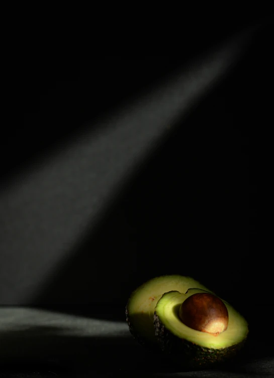 an avocado with some seeds cut open in the darkness