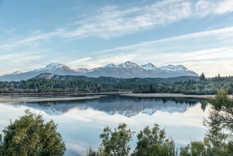 trees and bushes surrounding the water in the mountains