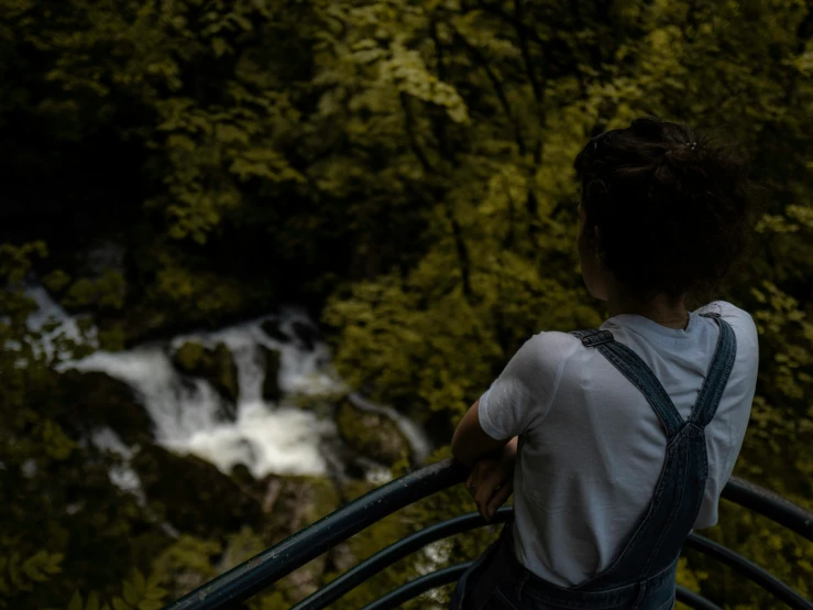 a girl looking out over a stream in the woods