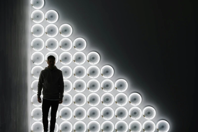 a man is standing in front of a light with circular objects