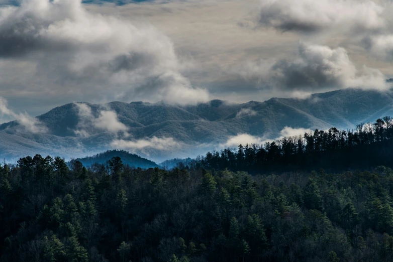 a dark mountain range with some clouds in the sky