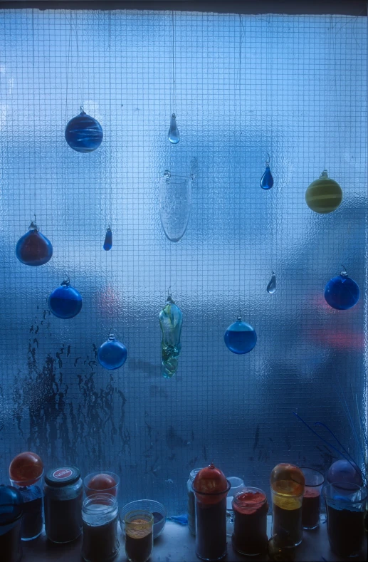 the view out the glass window has some colorful hanging balls