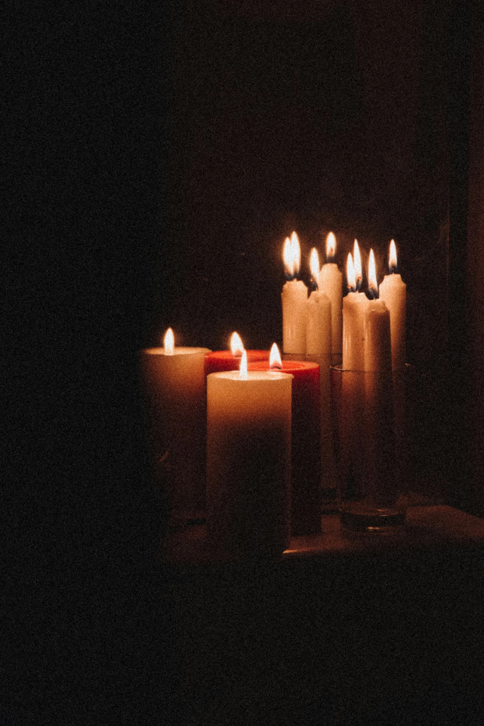 lit candles in the dark, with one glowing red