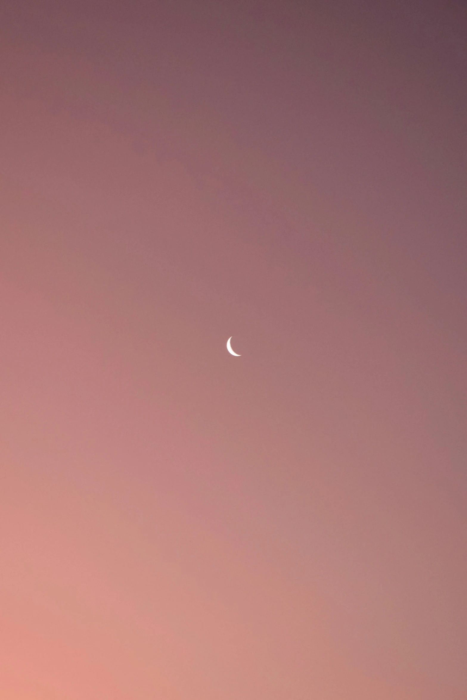 a view of the moon taken in the night sky with a pink hue