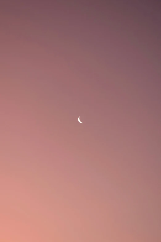 a view of the moon taken in the night sky with a pink hue