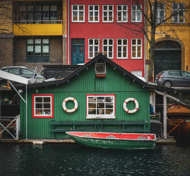 green houseboat with three red houses and a yellow and blue one