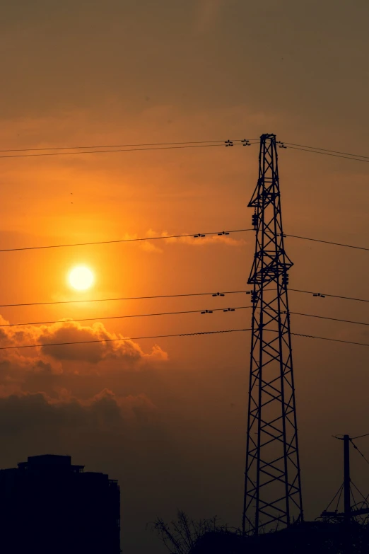 a sunrise is seen behind the power lines