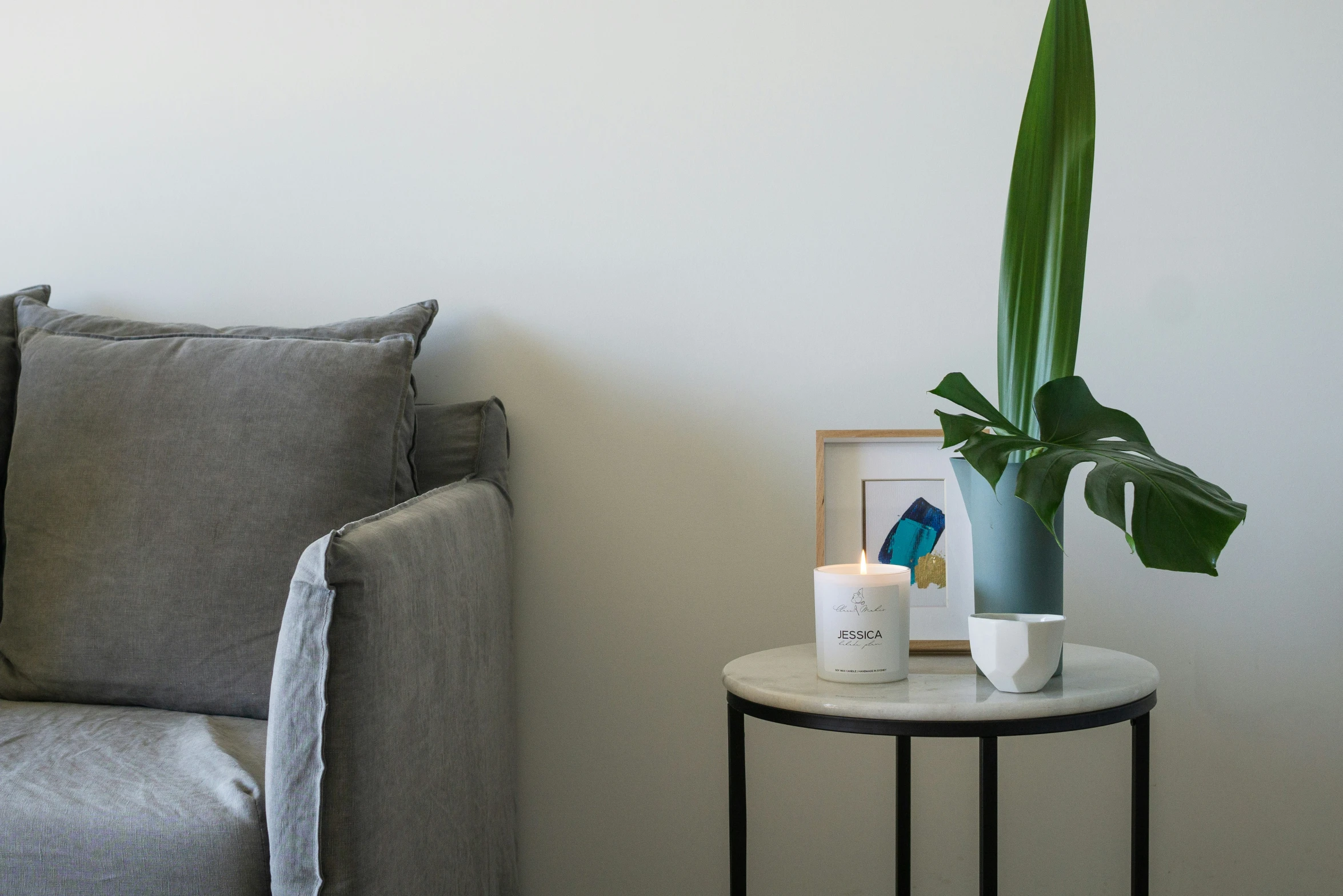 a plant in a vase sits on a small round table near the corner couch