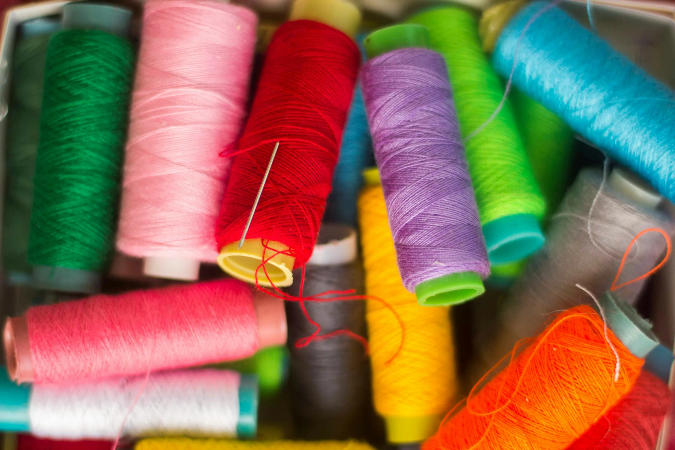 spools of different colored thread in a bin